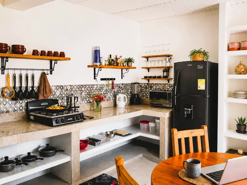Cocina con estufa, refrigerador, repisas con vajilla y utensilios