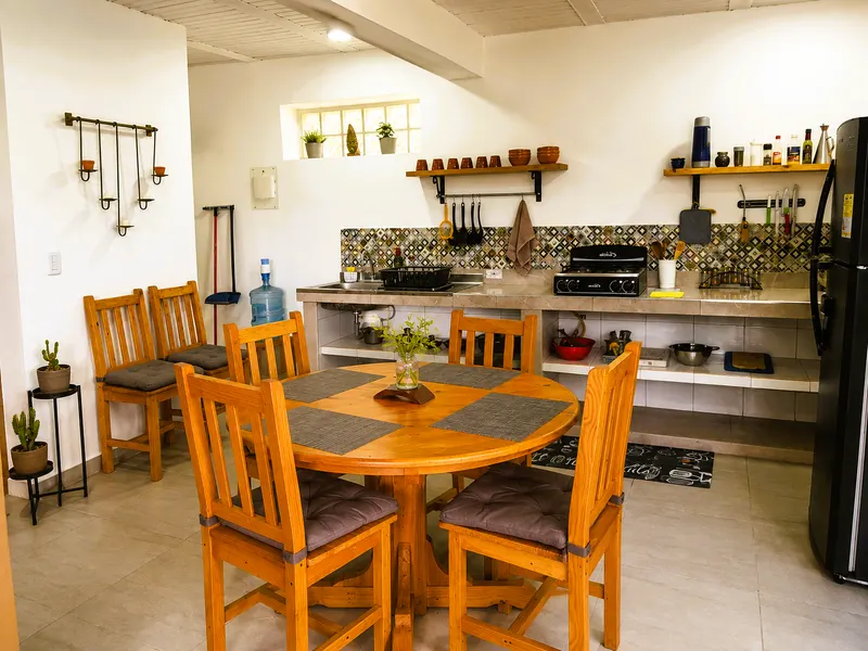 Mesa de comedor redonda de madera con cuatro sillas, junto a la cocina